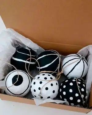 Bolas de Navidad artesanales de papel maché en color negro presentadas dentro de una caja.